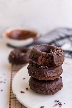 three chocolate doughnuts stacked on top of each other with one bite taken out