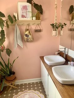 a bathroom with two sinks and plants on the wall above them, along with other accessories