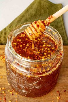 a jar filled with honey sitting on top of a wooden table next to a spoon