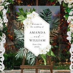 a wedding sign with white flowers and greenery