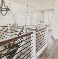 an open concept kitchen and dining room with white cabinets, wood flooring and chandelier