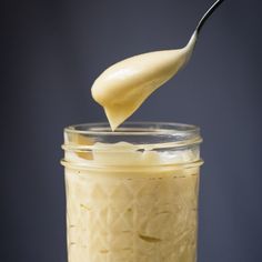 a spoon full of mayonnaise being drizzled into a jar