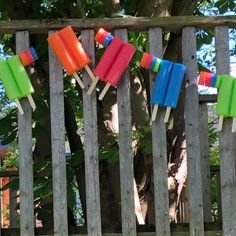 colorful popsicles hanging from clothes pins on a wooden fence