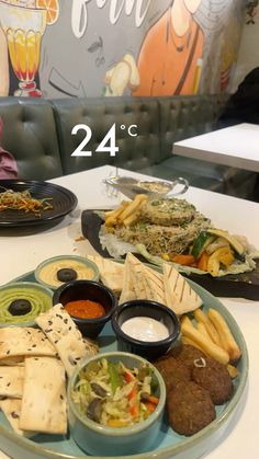 two plates with different foods on them sitting on a table next to a wall mural