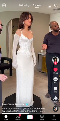 a woman in a white dress standing next to two men