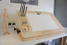 a wooden desk with a white board and pen holder next to it on top of a table