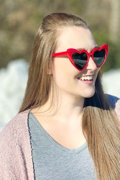 a woman wearing heart shaped sunglasses and smiling