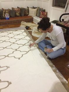 a woman sitting on the floor working on a rug