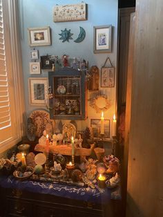 a room filled with pictures and candles on top of a blue tablecloth covered table