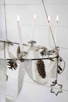 a chandelier with candles and pine cones hanging from it