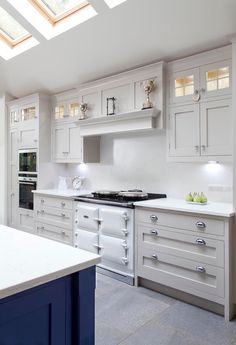 a large kitchen with white cabinets and blue counter tops on the island in front of an open skylight