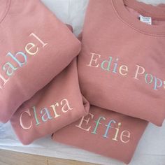 three pink shirts with embroidered names on them