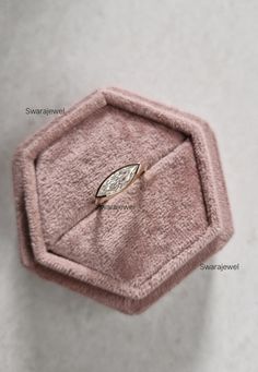 a pink velvet ring box with a diamond in it