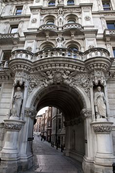 an ornate archway in the middle of a city street with statues on it's sides