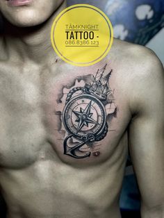 a man's chest with a compass tattoo on it and a yellow circle above the chest