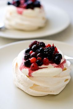 three small desserts on a white plate topped with berries