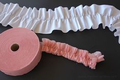 a roll of toilet paper next to a piece of pink ribbon on a black surface