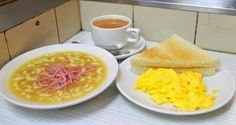 two white plates with food on them next to a cup of coffee and toasted bread