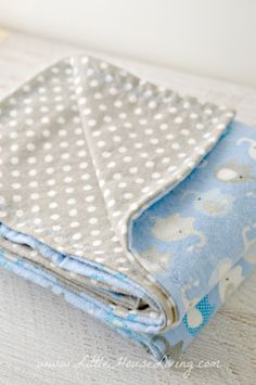 a blue and white blanket folded up on top of a wooden table next to a cup