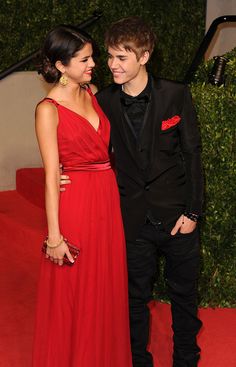 a young man and woman in formal wear standing next to each other on a red carpet