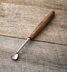 a wooden spoon with a metal handle on top of a wood table next to a bottle opener