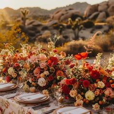 the table is set with flowers and place settings for an outdoor dinner party in the desert