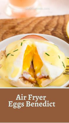 an egg benedict on a white plate with a fork and glass of orange juice in the background