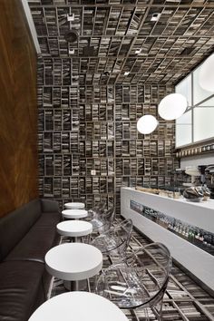 the interior of a restaurant with white chairs and black tile on the walls, along with bar stools