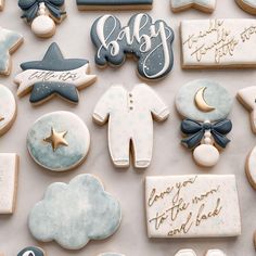 baby shower cookies are laid out on a white tablecloth with blue and gold decorations