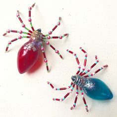 two spider figurines made out of beads and candy canes on a white surface