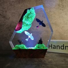 a glass display case with an image of bats in the air and moss growing inside