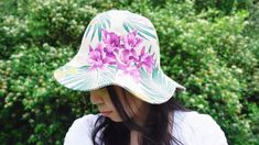 a woman with long hair wearing a white hat with purple flowers on the brim