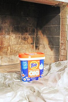 a bucket of ice cream sitting in front of a fire place with plastic covering it