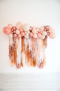 balloons and streamers are hanging from the wall in front of a white wall,