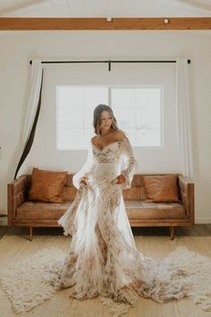 a woman standing in front of a couch wearing a wedding dress