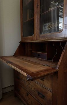 an old wooden desk with glass doors and drawers