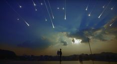 a man standing in front of a sky filled with stars and flares as the sun goes down