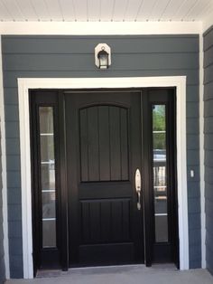 a black front door on a gray house with white trim and two side lit lights