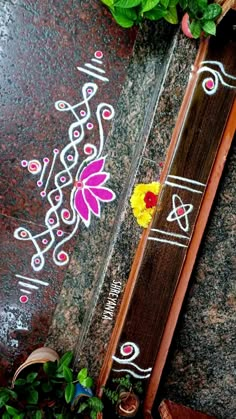 a wooden stick with flowers on it sitting next to some leaves and other items in the background