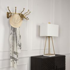 a hat is hanging on a coat rack next to a night stand with a lamp