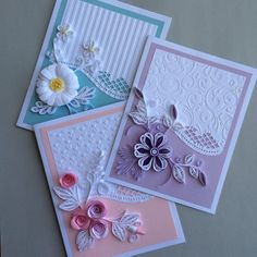 three cards with flowers on them sitting next to each other