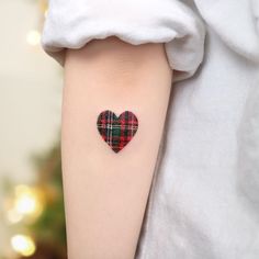 a small heart tattoo on the right upper arm, with a tartan plaid pattern