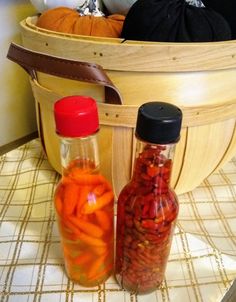 two bottles filled with pickles sitting on top of a table next to pumpkins