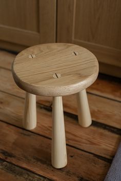 a small wooden stool sitting on top of a hard wood floor next to a door