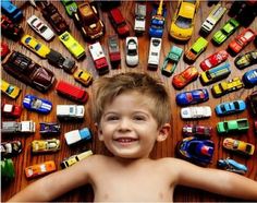 a young boy standing in front of a bunch of toy cars