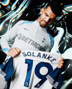 a man holding up a soccer jersey with the number 19 on it