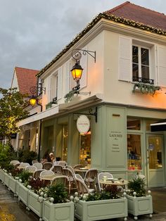 an outdoor cafe with tables and chairs on the sidewalk in front of a building at dusk