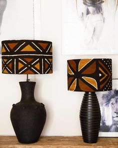 two lamps are sitting on a shelf next to an animal print lamp shade and a black vase