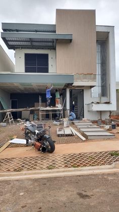 a motorcycle parked in front of a building under construction with people working on the roof