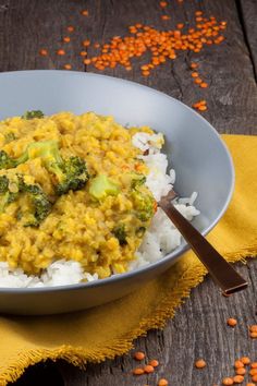 a bowl filled with rice and broccoli on top of a wooden table